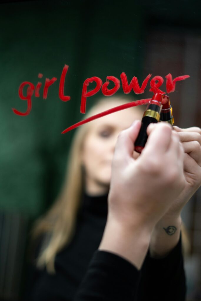 Close-up of 'girl power' written with lipstick on mirror symbolizing empowerment and feminism. Selbstfürsorge für Frauen*